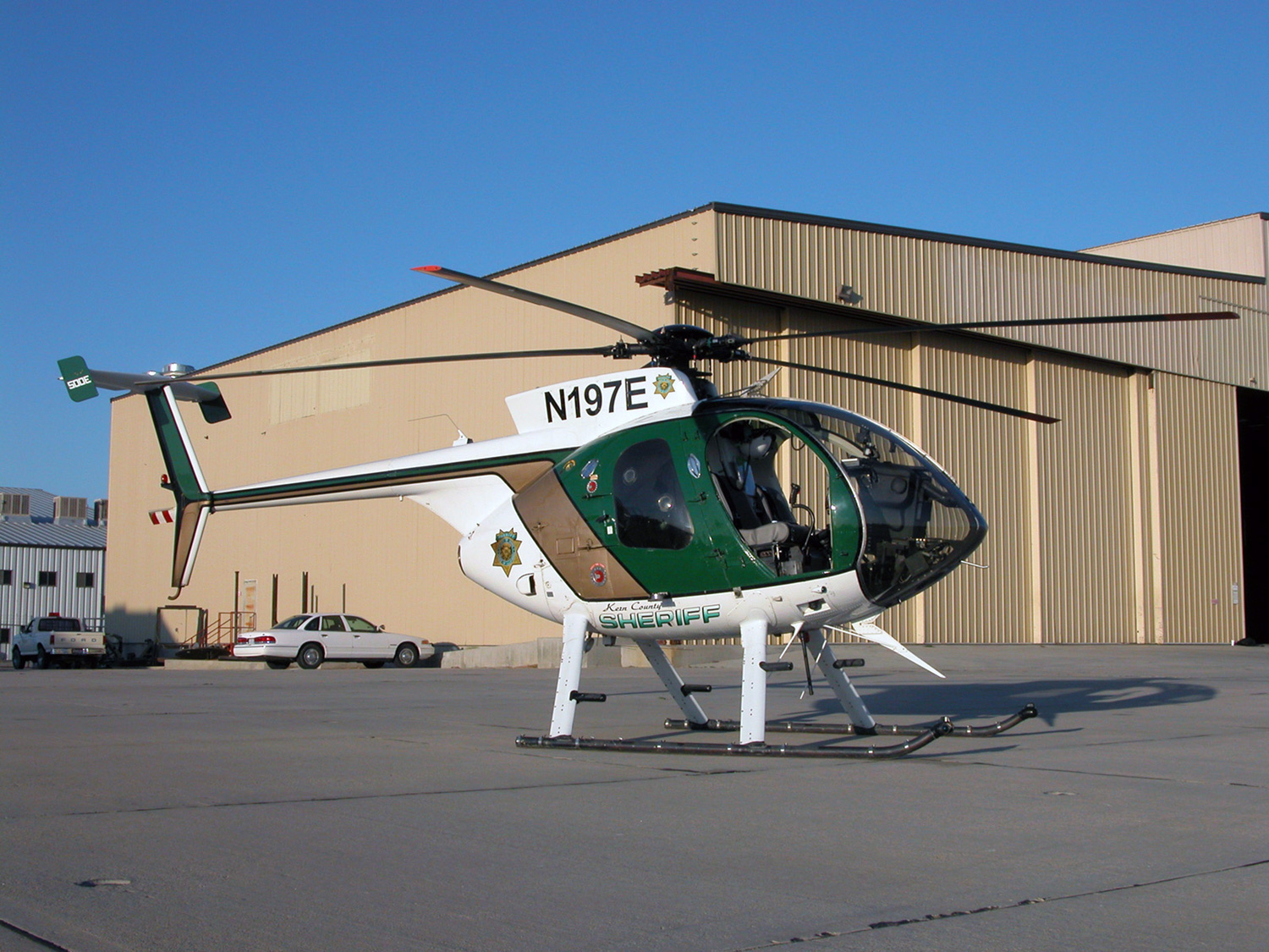 Photo of sheriff livery on a Hughes 500 with hangars as the backdrop