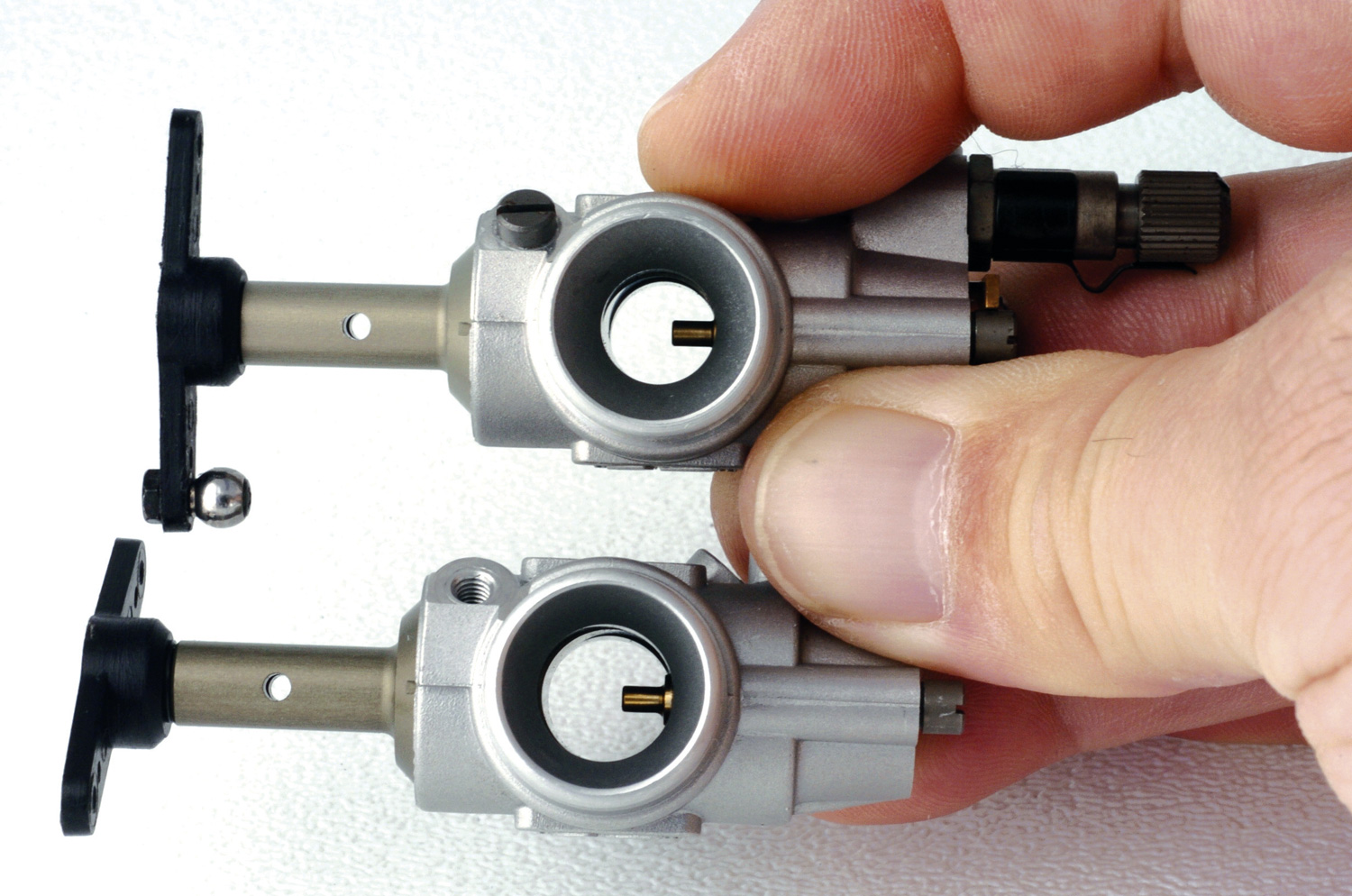 Close up photo of two helicopter carburetors showing difference in internal bore