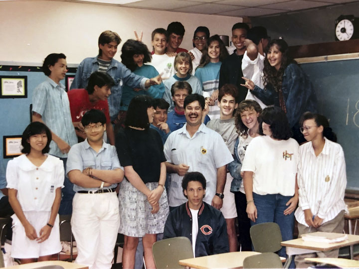 A wide angle shot of a John and a group of his 8th grade math students
