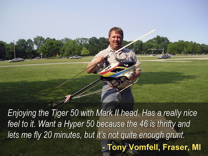 Man standing in a field holding Audacity Models Tiger 50 model helicopter