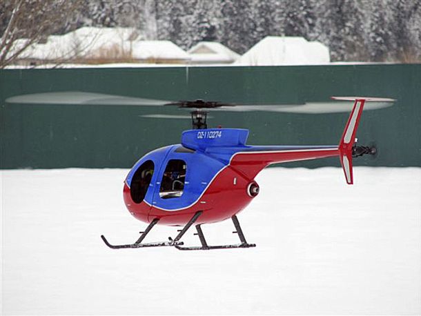 Outfitted with Audacity Models Pantera P6 mechanics, a red, white, Outfitted with Audacity Models Pantera P6 mechanics, a red, white, and blue fiberglass model of the Hughes 500 hovers slowly over a snow covered field against a backdrop of a green fence.and bluemodel of a Funkey-brand Hughed 500 fiberglass fuselage reproduction of the famous Hughes 500 is painted in hovers over a snow covered field